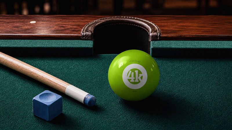 Free billiard ball mockup PSD with glossy green pool ball, wooden cue, blue chalk, and dark green table cloth.