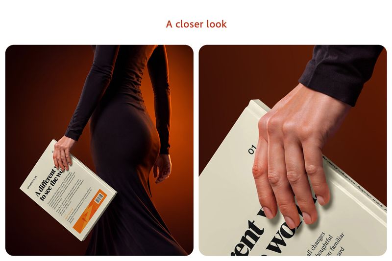 Close-up of a woman's hand holding the back cover of an A4 hardcover book beside a black dress under warm orange rim lighting.