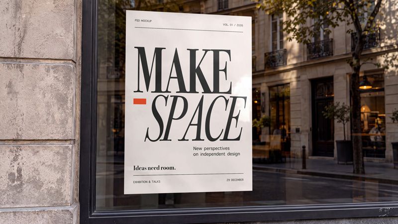 Shop window poster mockup with black MAKE SPACE lettering on cream paper and reflected buildings in the glass